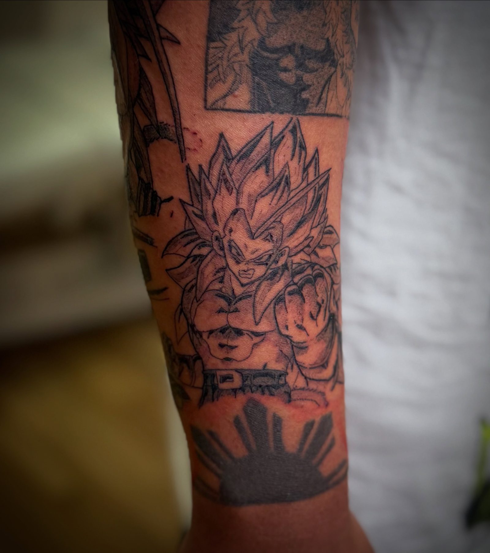 Goku from Dragon Ball tattooed in black and grey on a forearm