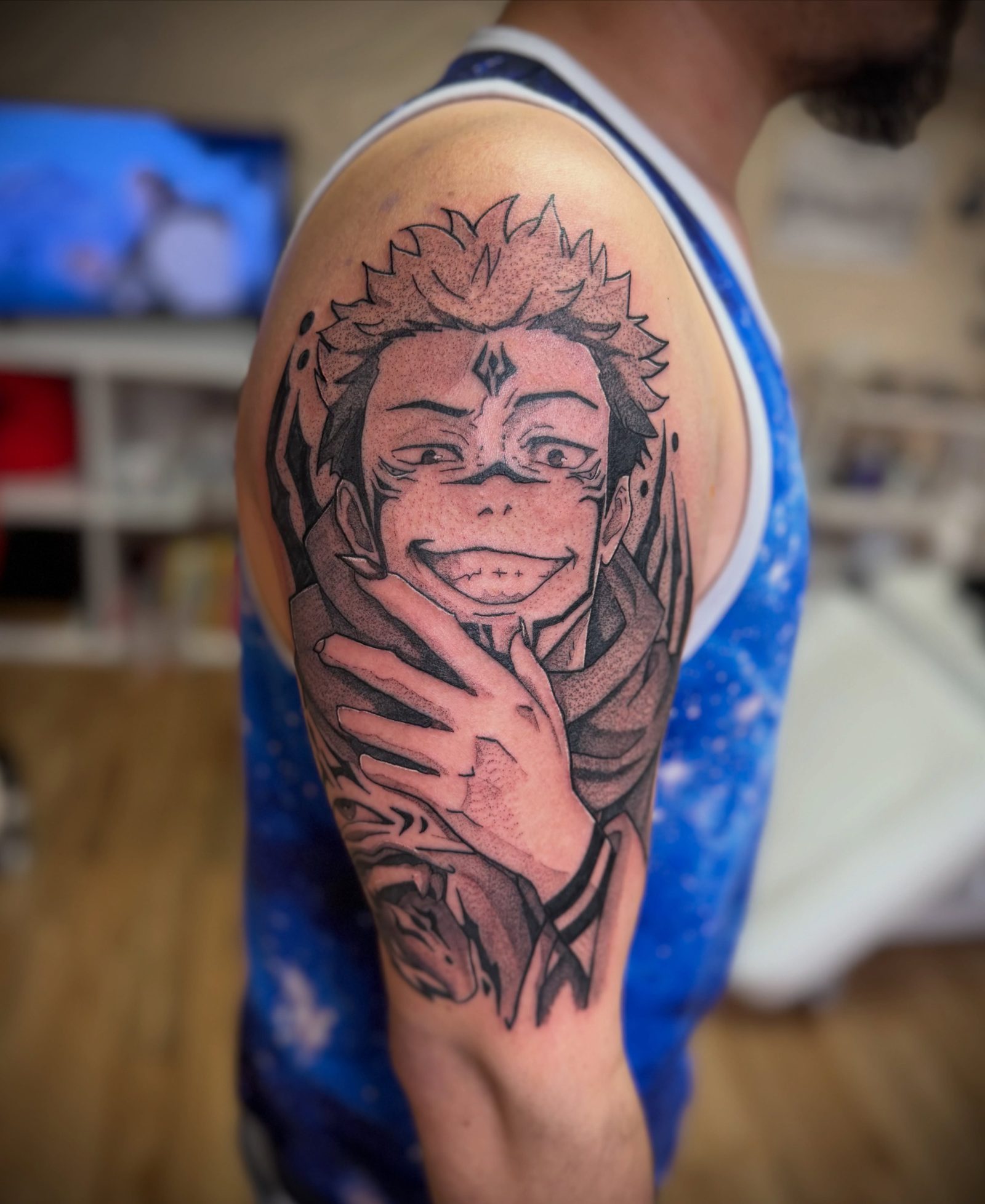 Sukuna from Jujutsu Kaisen tattooed in black and grey on an upper arm